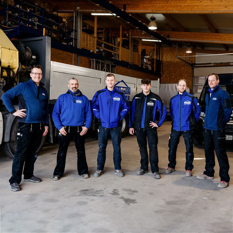 Team der Zimmerei Latteier - 6 Zimmermänner stehen in der Holzhalle